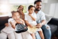 Closeup of remote control with family watching tv in their living room together. Parents and kids relaxing on the sofa Royalty Free Stock Photo