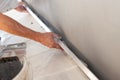 Closeup of repairman hand plastering a wall with long trowel.