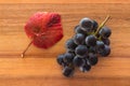 Bunch of ripe Cabernet Sauvignon grapes with red leaf on wooden chopping board