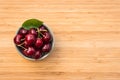 Ripe dark red cherries in porcelain bowl on wooden chopping board with copy space on right Royalty Free Stock Photo