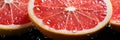 closeup ripe juice sliced red grapefruit in water drops top view banner
