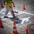 Closeup of road worker preparing a white pictogram at a street with orange cones for safety & x28;square& x29;