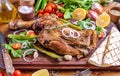 Closeup of a roast leg of lamb on the wooden cutting board under the natural light Royalty Free Stock Photo