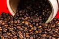 Closeup roasted coffee beans in a barrel isolated on a red background