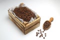 Closeup of roasted coffee beans in a small wooden crate, isolated on white background. With wooden spoon. Royalty Free Stock Photo