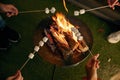 Closeup roasted marshmallows on skewers over open camping bonfire