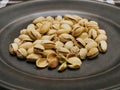 Closeup of roasted pistachio nuts on plate on plaid placemat Royalty Free Stock Photo