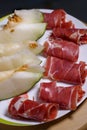 Closeup of rolled slices of cured pork ham jamon with melon