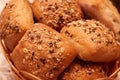 Closeup of rolls of freshly baked bread topped with grains, in a wicker basket Royalty Free Stock Photo