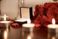 Closeup of romantic engagement ring box, fresh red roses and candles in an empty room at night. Getting ready and