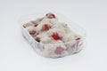 Closeup of rotten moldy raspberry in plastic box isolated on white background