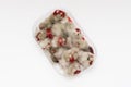 Closeup of rotten moldy raspberry in plastic box on white