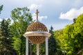 Closeup of a round cross surrounded by greenery at the Chisinau Cathedral Park in Moldova