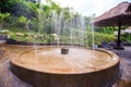 Round Stone Fountain Jets by Reed Umbrella in Park Royalty Free Stock Photo