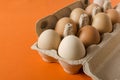 Closeup of rows of fresh eggs in the box on the bright orange background