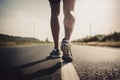 Closeup of runner shaved feet in running shoes going for a run on the road at sunrise or sunset.