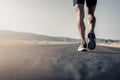 Closeup of runner shaved feet in running shoes going for a run on the road at sunrise or sunset.