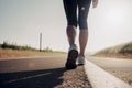 Closeup of runner shaved feet in running shoes going for a run on the road at sunrise or sunset.