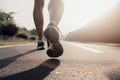 Closeup of runner shaved feet in running shoes going for a run on the road at sunrise or sunset.