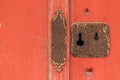 Closeup of rusted antique keyhole and lock on red wooden door Royalty Free Stock Photo