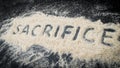 Closeup of SACRIFICE word written on white sand Royalty Free Stock Photo