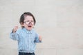 Closeup sad asian kid cry because he want something on marble stone wall textured background with copy space Royalty Free Stock Photo