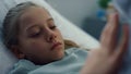 Closeup sad little patient touching soft toy in ward. Sick kid missing parents. Royalty Free Stock Photo