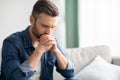 Closeup of sad man sitting on couch at home Royalty Free Stock Photo