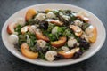 Closeup salad with nectarines, mozzarella and mixed greens in white plate on concrete background