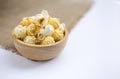 Closeup salted popcorn in round wooden bowl on white background