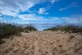 Closeup of the sandy path toward the ocean on Virginia beach with a blue sky background