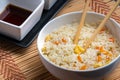 Closeup of sauces and a bowl of cooked rice with vegetables and chopsticks on the table Royalty Free Stock Photo