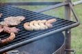 Closeup of sausages and beef grilling on an outdoor grill in a park