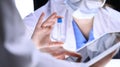 Closeup of scientific research team with clear solution in laboratory. Blonde female chemist holds test tube of glass