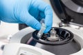 Closeup of a scientist hand placing a tube into an small table centrifuge. Spin column-based nucleic acid purification technique.