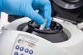 Closeup of a scientist hand placing a tube into an small table centrifuge. Spin column-based nucleic acid purification technique
