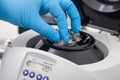Closeup of a scientist hand placing a tube into an small table centrifuge. Spin column-based nucleic acid purification technique