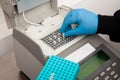 Closeup of a scientist hand while working at the laboratory with a thermal cycler. Polymerase chain reaction technique. PCR