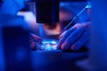 Female researcher preparing for cell handling with micromanipulation equipment