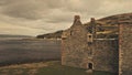 Closeup Scotland castle walls aerial. Summer seascape at green mountains. Tourist attraction
