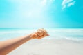 Closeup on sea shell in hand of woman on seashore