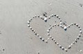 Closeup Sea shell make arranged hearts shape on gray sand beach with sun light on summer Royalty Free Stock Photo