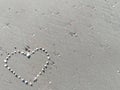 Closeup Sea shell make arranged hearts shape on gray sand beach with sun light on summer Royalty Free Stock Photo