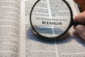 closeup of the second book of Kings from Bible or Torah using a magnifying glass to enlarge print.