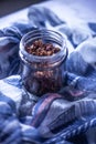 Healthy crunchy multi-seed topping in a glass jar sitting on a beautiful feminine scarf