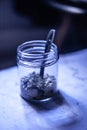 Raw seeds in a glass jar with a stainless steel measuring spoon in a dim kitchen