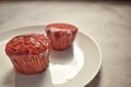 A Closeup selective focus Picture of a Red Velvet cup cake on a white Plate.
