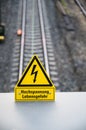 Closeup selective focus shot of a yellow warning sign on a railway background
