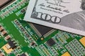 Closeup of semiconductor circuit board and 100 dollar bill