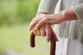 Closeup of a senior disabled womans hands holding a cane outside in garden or park. Older female learning to walk after